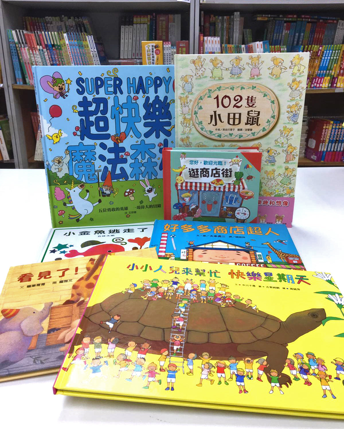 Colorful Chinese children's picture books with illustrated covers displayed on a table in a bookstore.