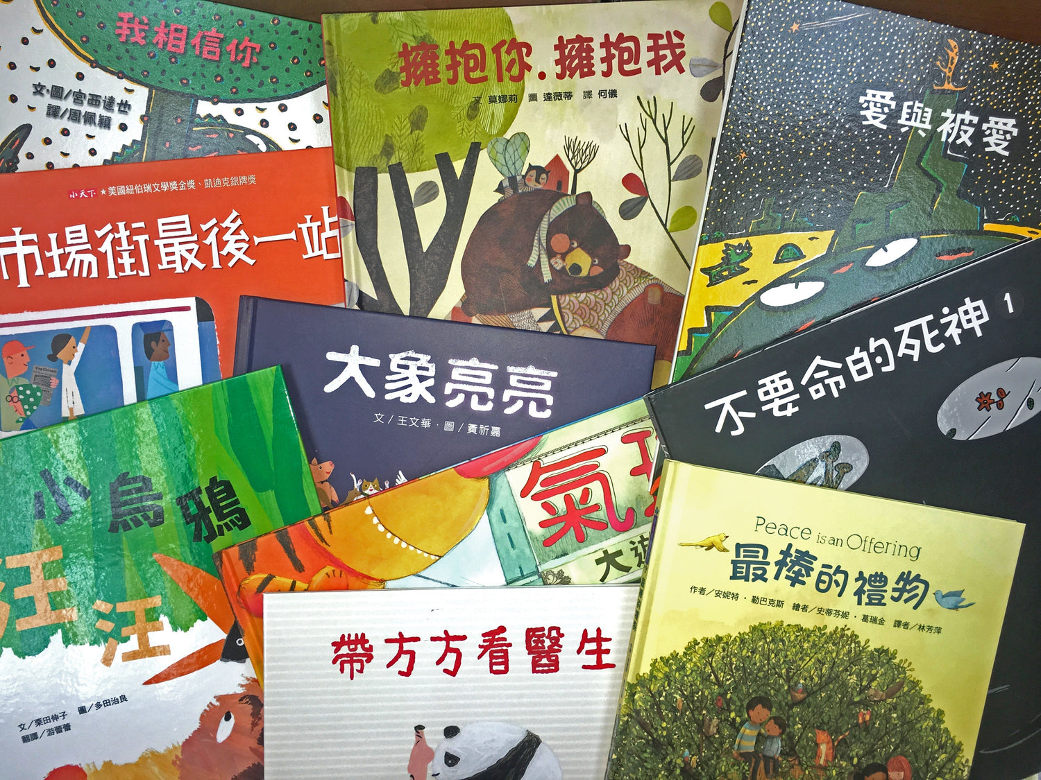 Assorted colorful Chinese children's picture books arranged on a wooden surface.
