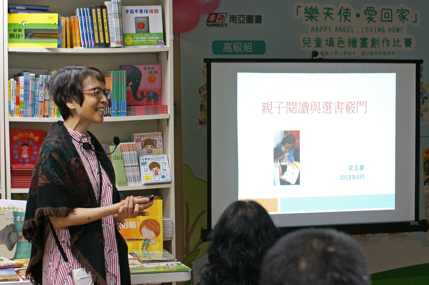 Woman giving a parent-child reading workshop in front of a bookshelf with children's books