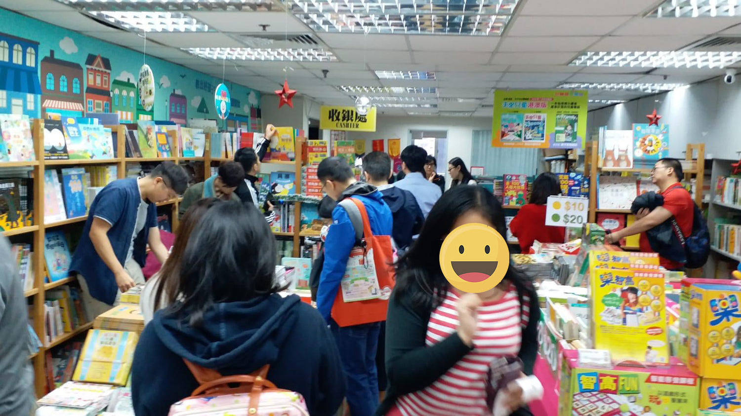 Busy children’s bookstore with customers browsing shelves of educational books and learning games.