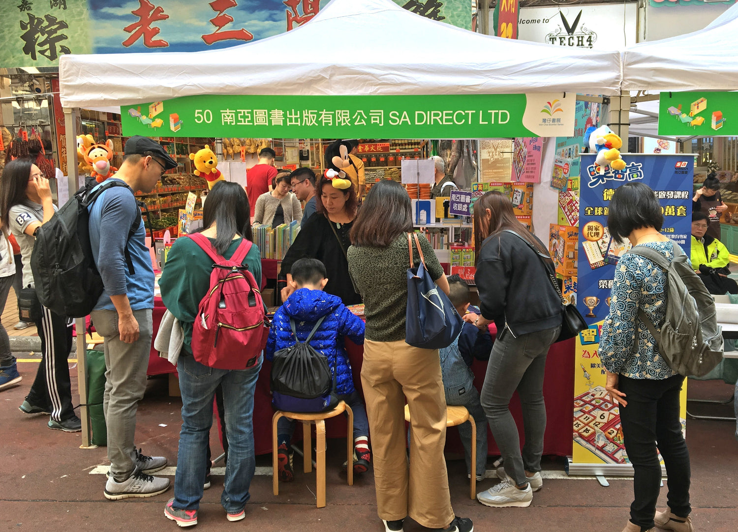 People at a street fair booth selling children's books and educational toys, educational event