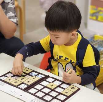 一位穿著黃黑色上衣的男孩，在活動中專心致志地玩著智高FUN遊戲。