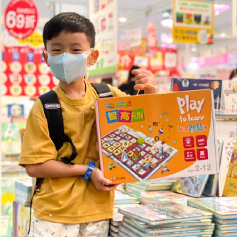 一位戴著口罩的小男孩在書展自豪地展示他新買的智高FUN課程。