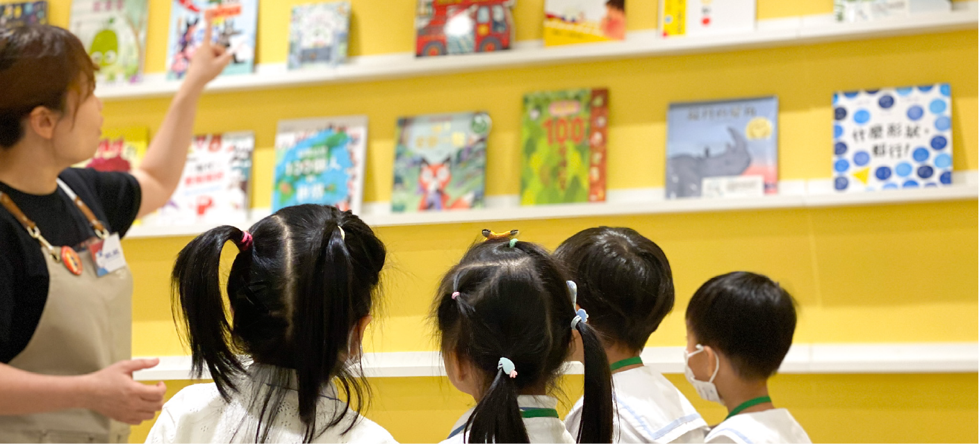 幾位小女孩在南亞圖書繪本館的黃色書架前，專心地挑選書籍。