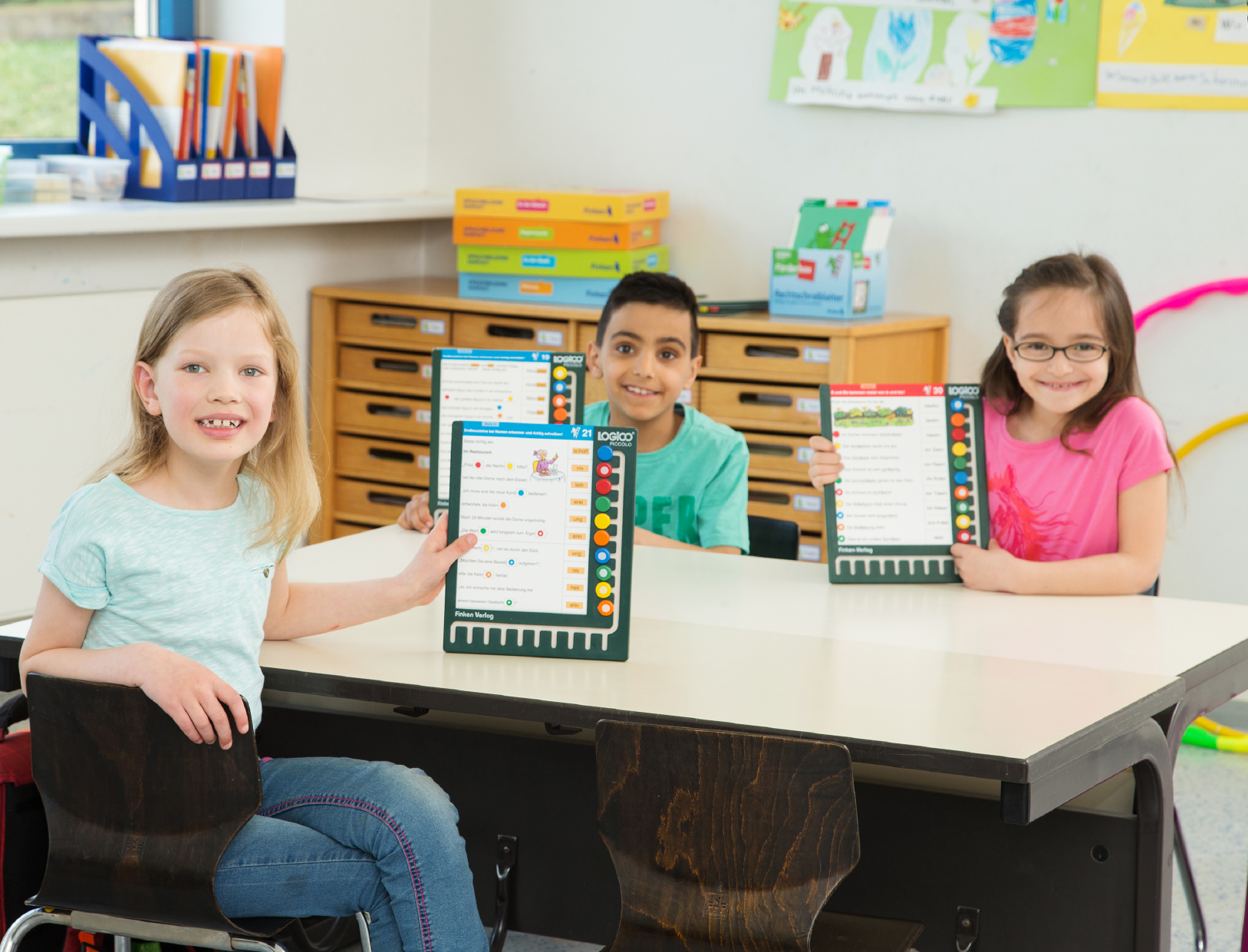 Three students learning together with LOGICO boards in a classroom at school.