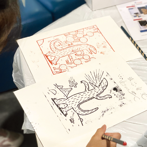 學生在版畫工作坊中專心創作，描繪書中的角色霸王龍。