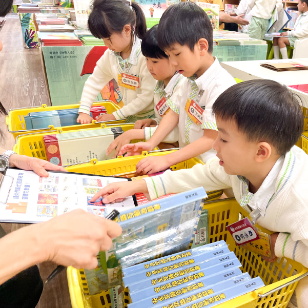 小小店長活動，幾位幼稚園學生正在從書籃中挑選自己喜愛的書籍，進行圖書整理任務。